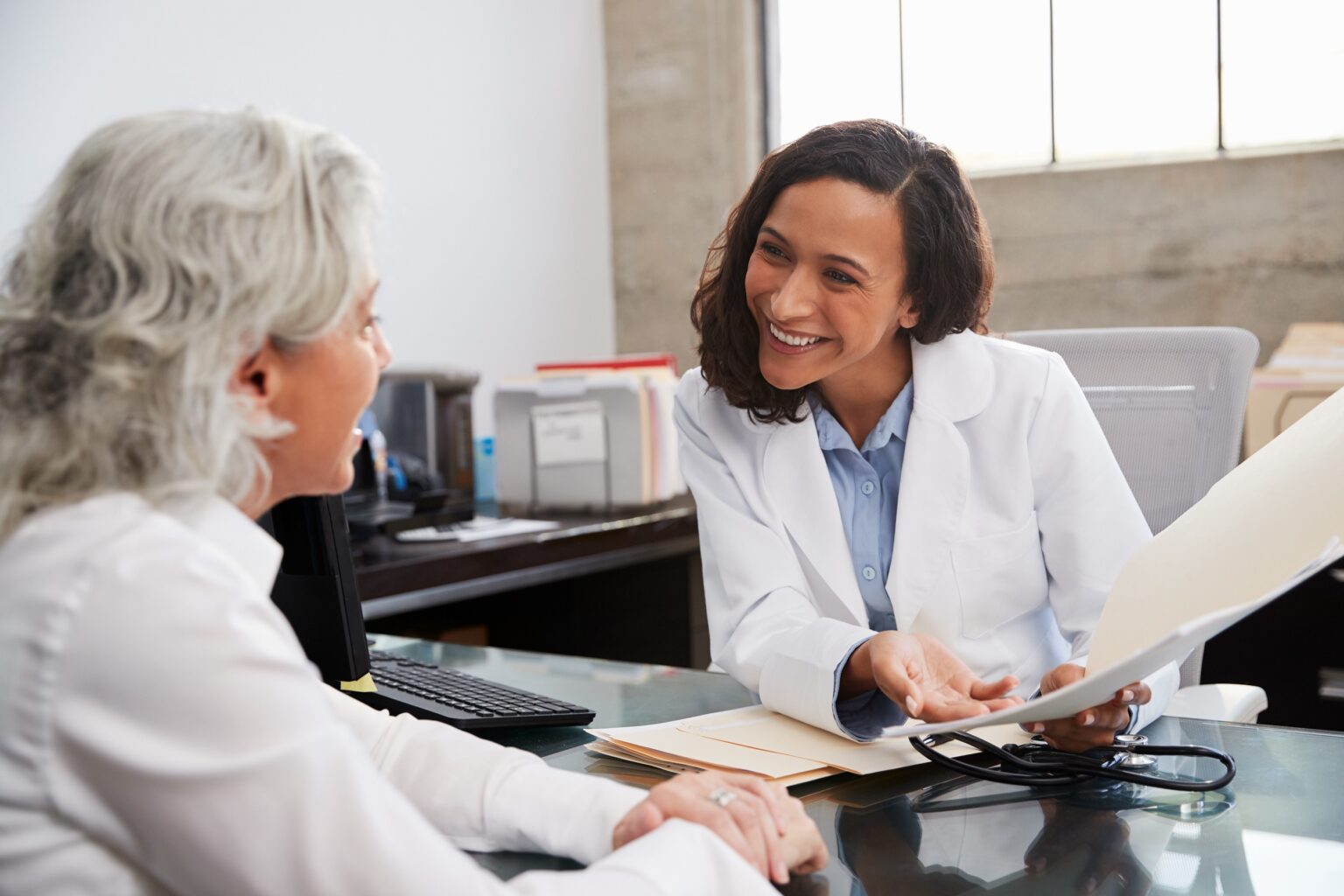 Smiling female doctor in consultation with senior patient